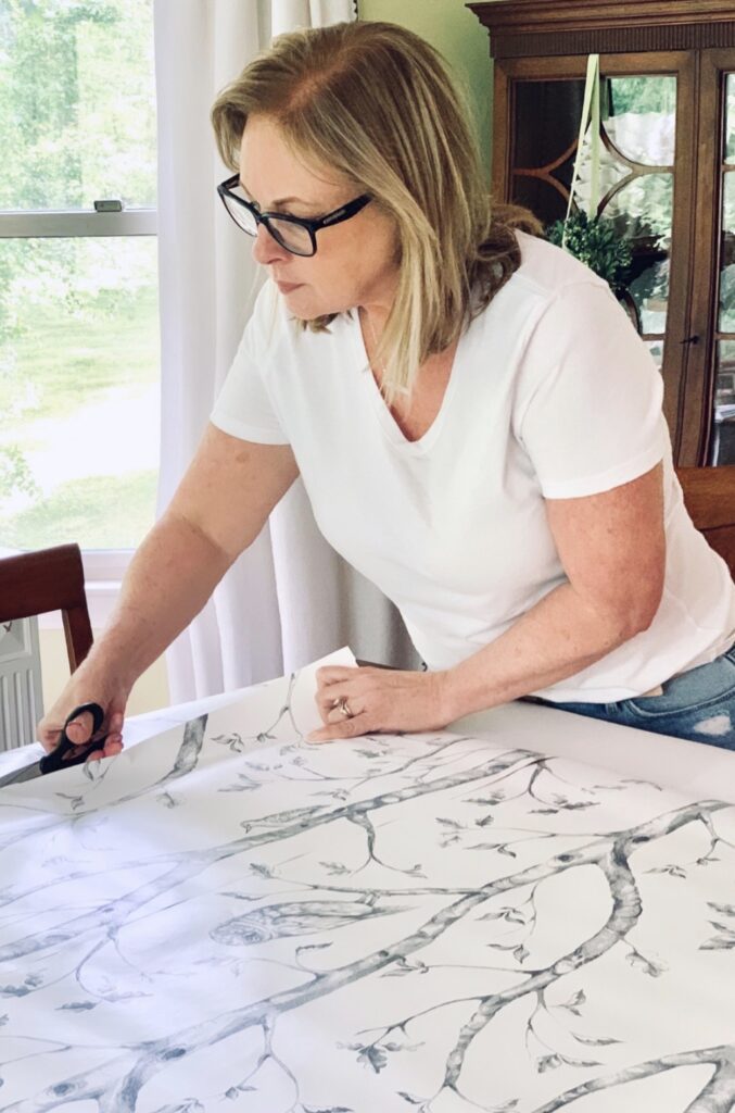 me cutting wallpaper for my diy fireplace cover.