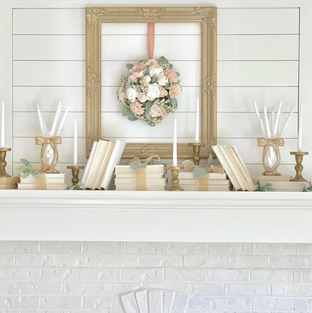 white mantel with overmantel with books laying across the mantel. the design includes gold, cream and peach tones.
