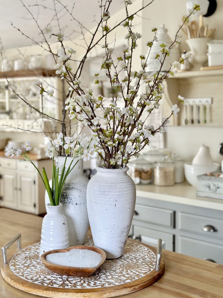 tall white ceramic vases with branches in them. 