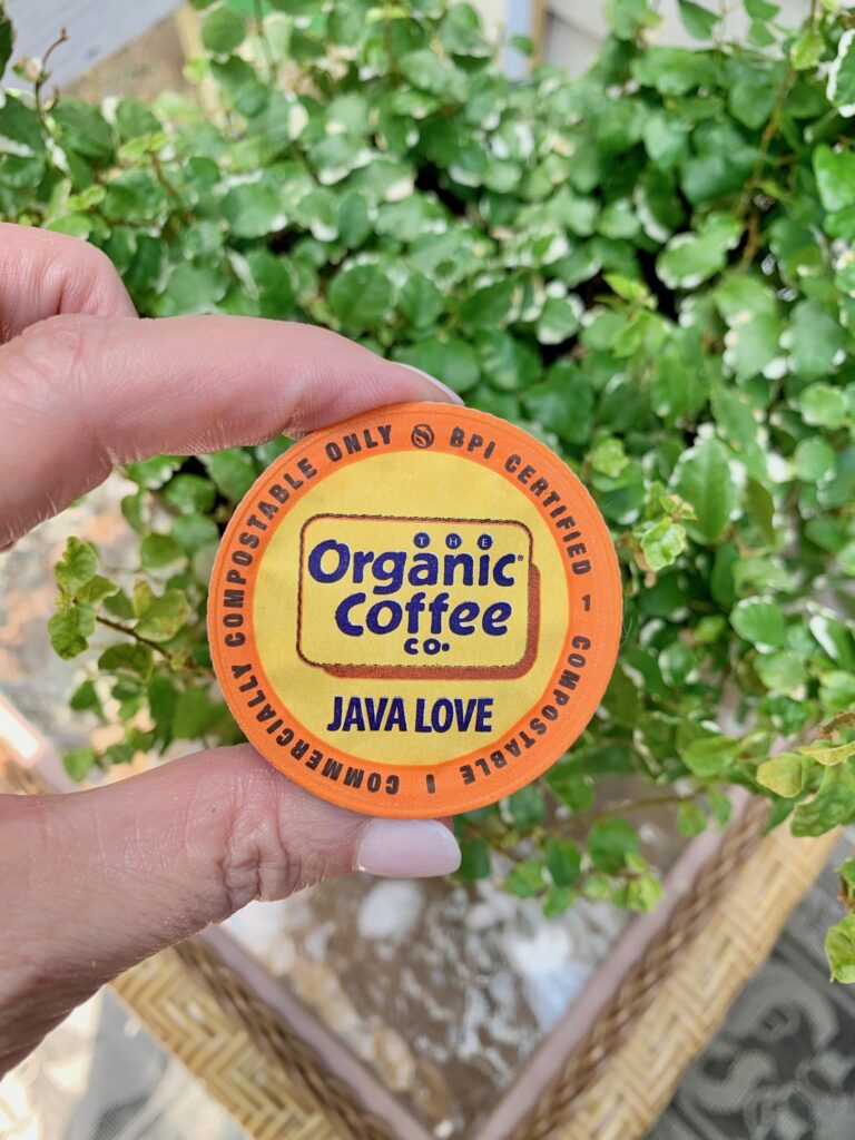 me holding one of my organic coffee pods in front of a plant. 