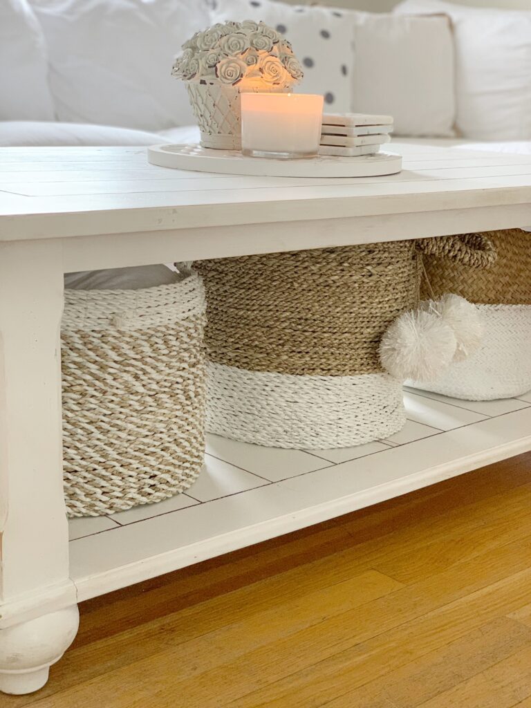 A coffee table with baskets underneath holding blankets. 