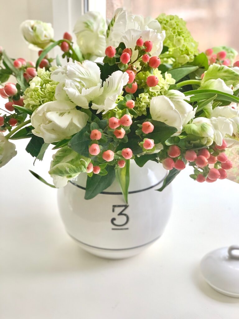 a white canister with the number 3 on it filled with fresh flowers. 