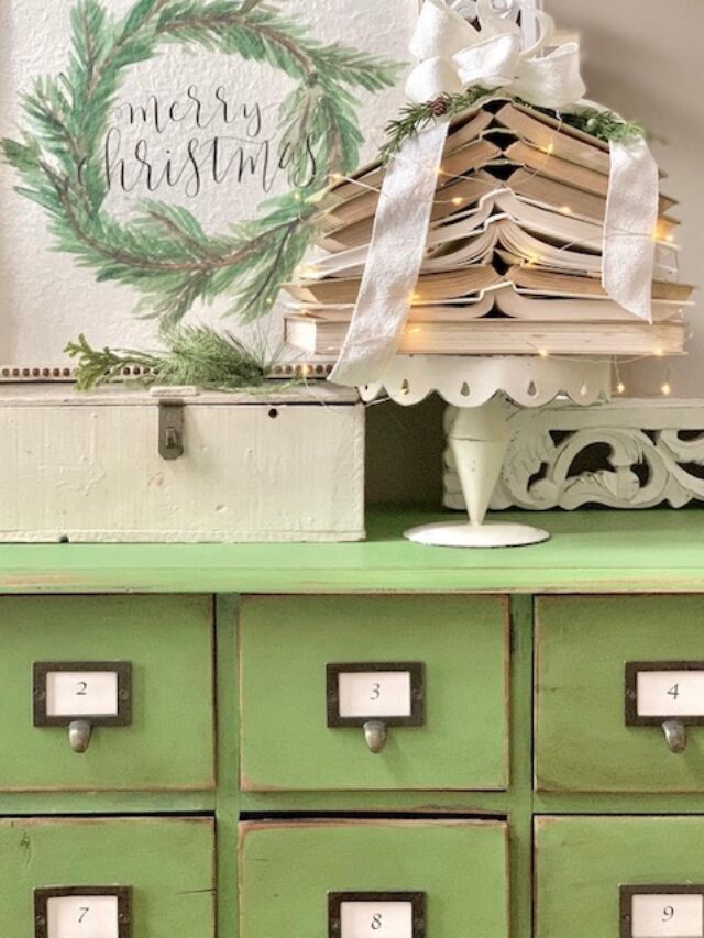 an apothecary holding a cream color cake stand with green books stacked like a christmas tree.