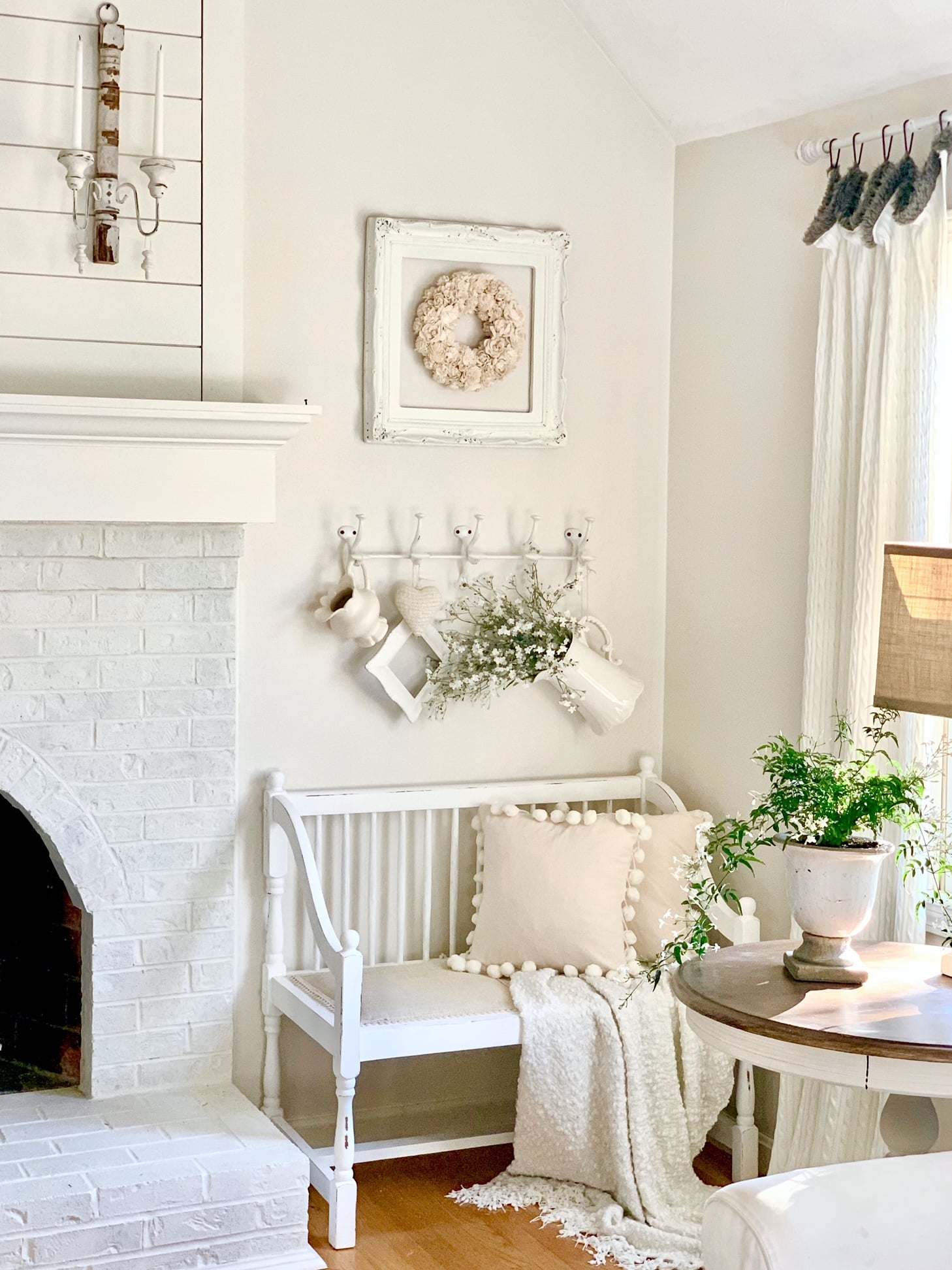 Living room photo with an indoor  jasmine plant sitting on an end table. Also in photo is a bench, pillows and decor. 