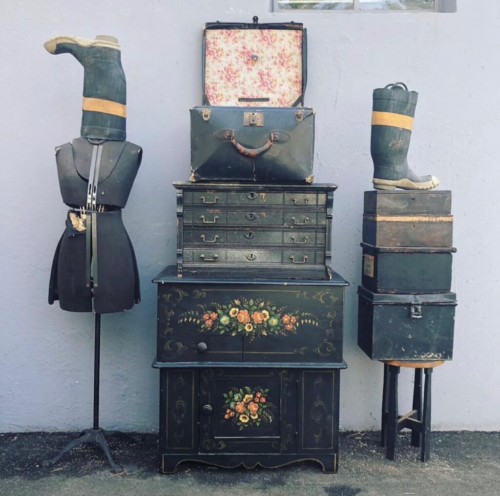 A cabinet, with a chest of drawers with fireman boots and a suitcase. 