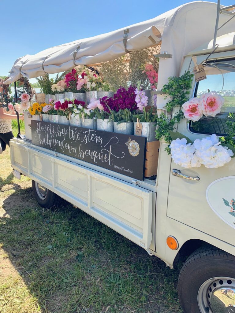 an old truck filled with flowers to purchase. 