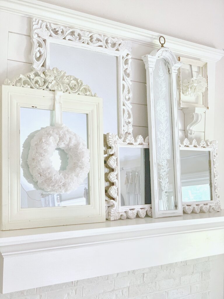 Layered mirrors on my mantel. All the mirrors have white and cream colored frames. the Easy DIY Cupcake Liner Flower Wreath is hanging on one of the mirror fronts. 