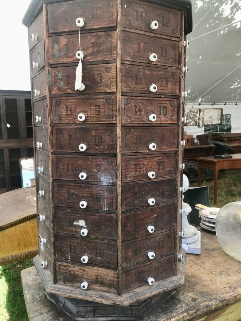 A dark wood spinning tower apothecary with tiny white knobs. 