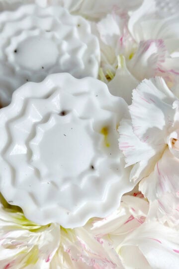 2 flower shaped soaps with herbs showing in them.