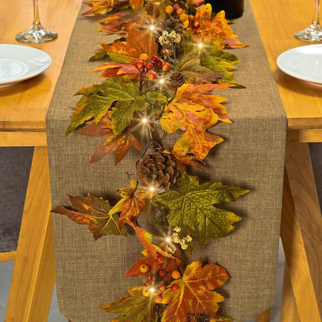 a tradition leave fall garland with lights and pinecones. this one is running down the center of a table. 