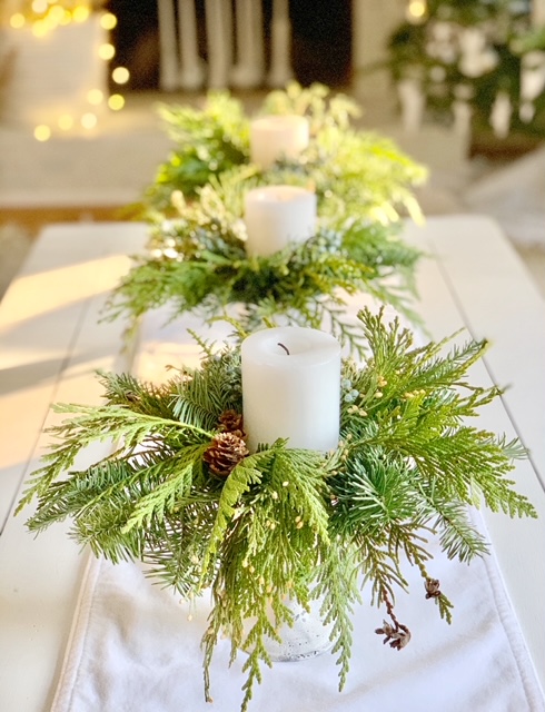 white small urns filled with fresh cedar with a candle on top. 