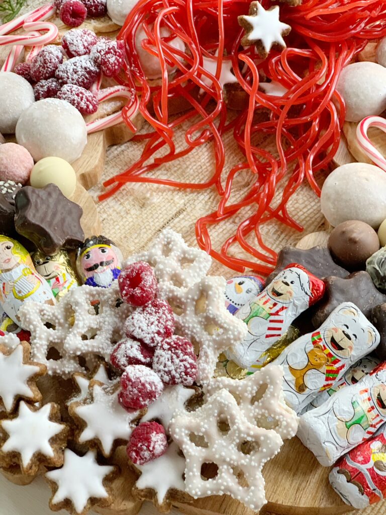 a close up of the candies and cookies on a wooden wreath board for this Holiday Dessert Charcuterie Wreath Recipe post. 