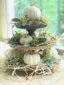 3 stacked trays with pumpkins, raffia and greens.