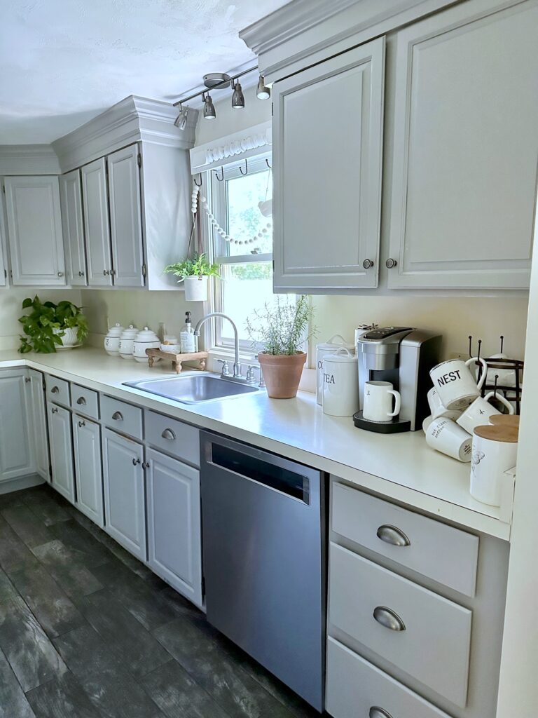 a full view of the sweep of cabinets and counter top with a variety of decor and a coffee maker. 