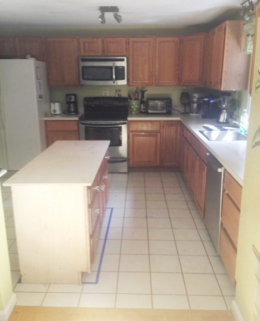 The before picture of old standard stock oak cabinets in a dark kitchen.