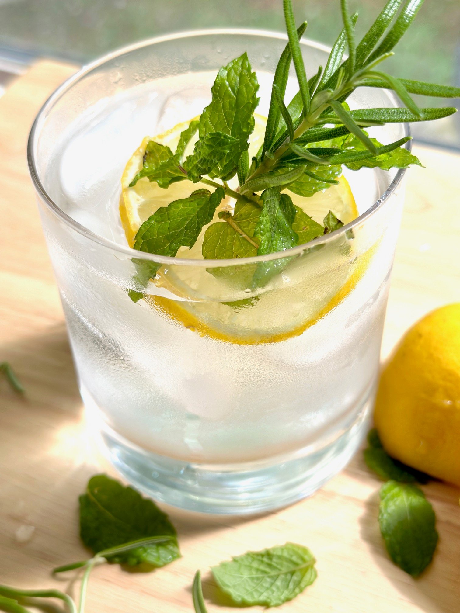 a glass of ice water with lemon and mint garnish. 