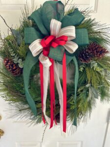 a front view ofthe wreath with the over the top green, cream and red layered bow.