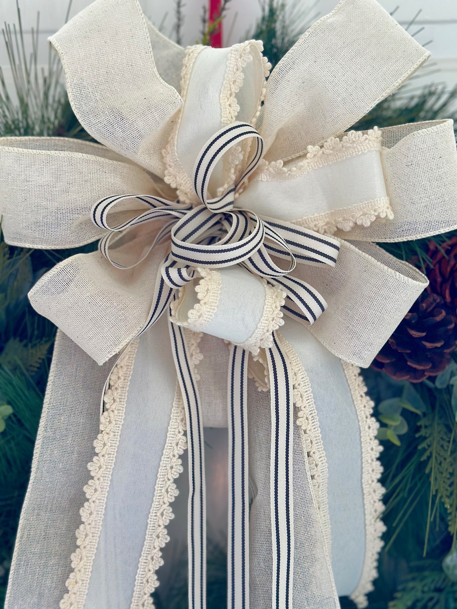 Close up of a cream colored layered bow. The small ribbon is not wired but is supported by the wired ribbon it sits on.
