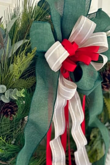 A green, white and red layered bow on a Christmas wreath.