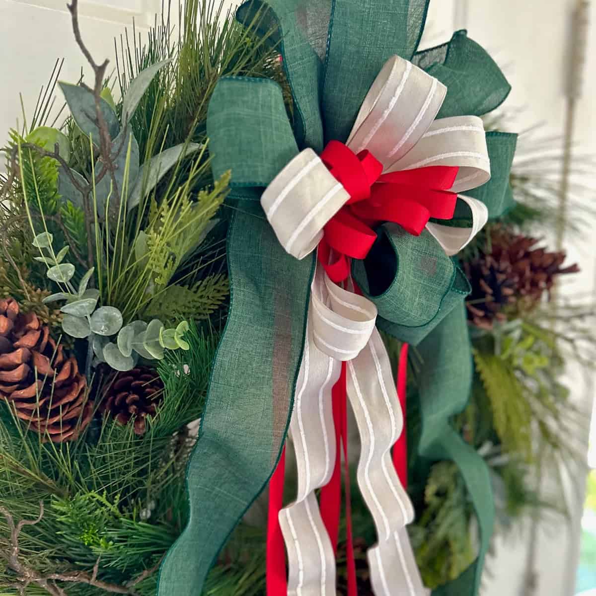 A green, white and red layered bow on a Christmas wreath.