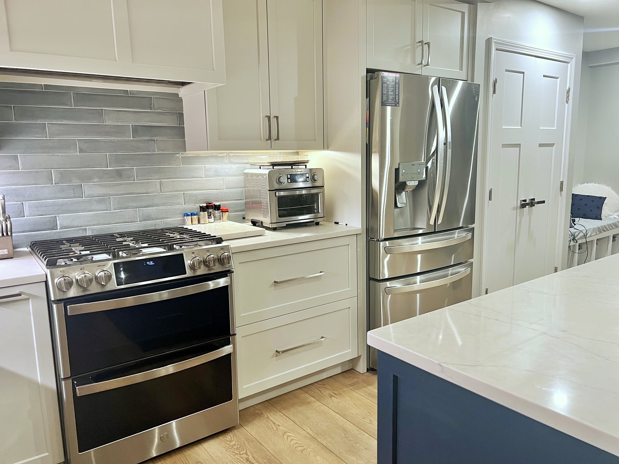 a bright blue island with white cabinets. both have the same white stone counter top.
