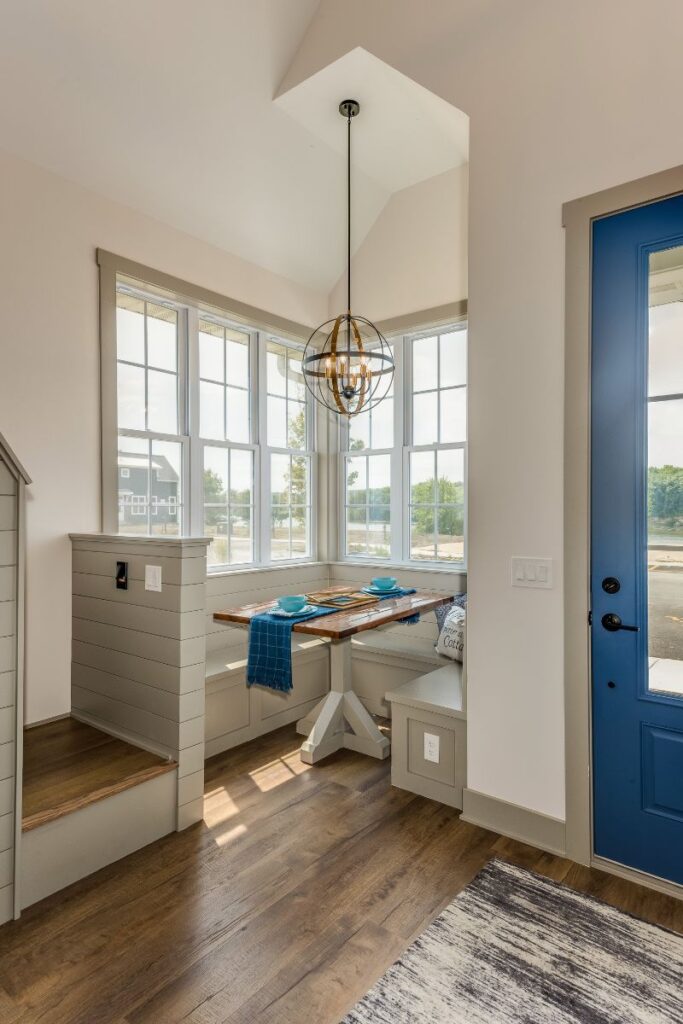 a kitchen nook in a pretty shiplap kitchen with a bright blue back door. floors are hardwood. 