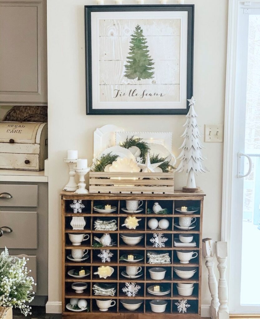 An antique cubby with white dishes, snowflakes and candles in each cubby. 