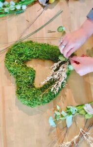 a moss heart shaped wreath with me using my glue gun to add faux flowers.