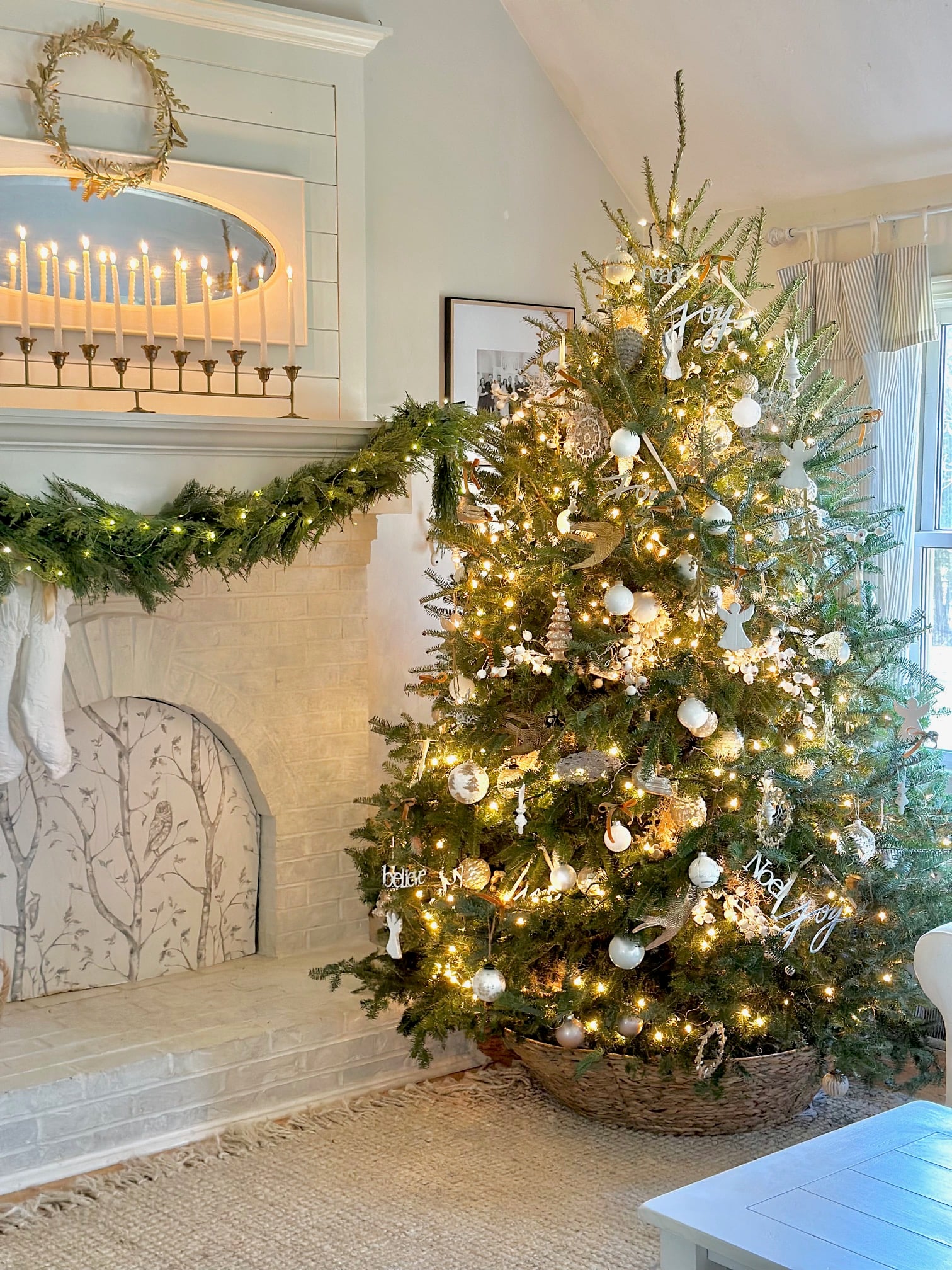 A large fresh Christmas tree with lights and ornaments sitting in what looks like a wicker basket. 