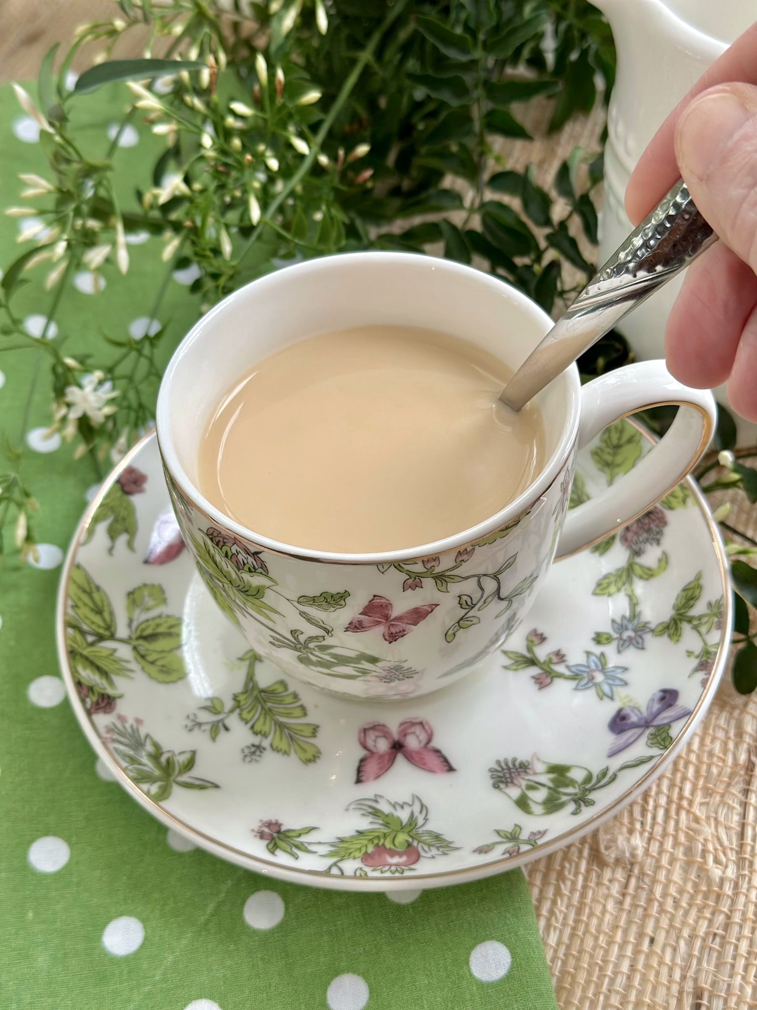 Stirring milk in tea that is in a tea cup. 