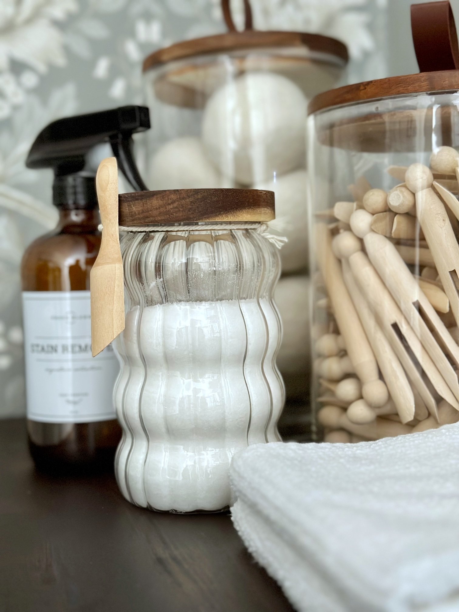 Laundry scent boost in a glass jar with other laundry supplies. 