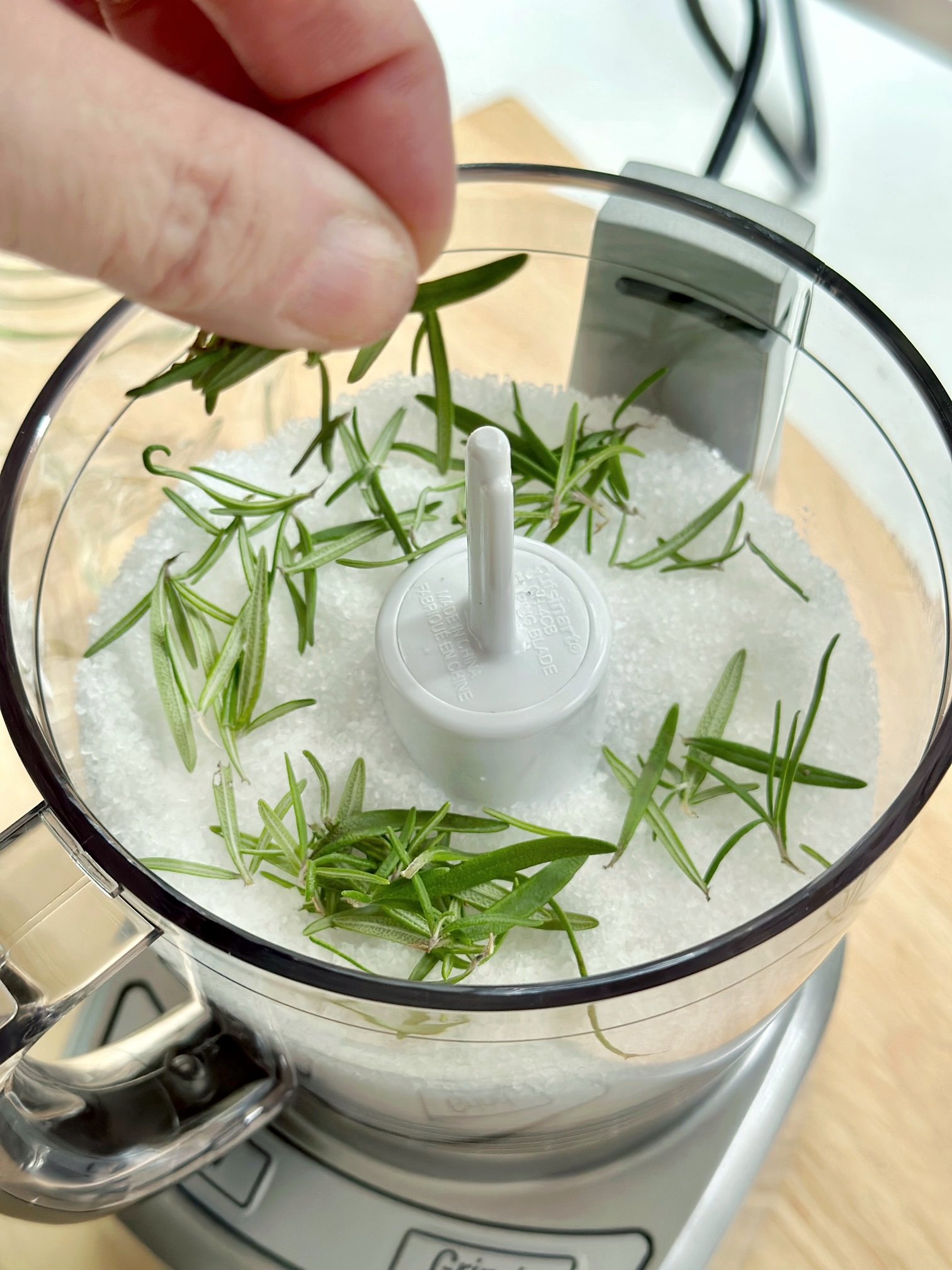 Putting died rosemary in the food processor with salt. 