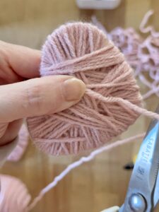 with scissor cutting the end of the yarn on the back of the heart.