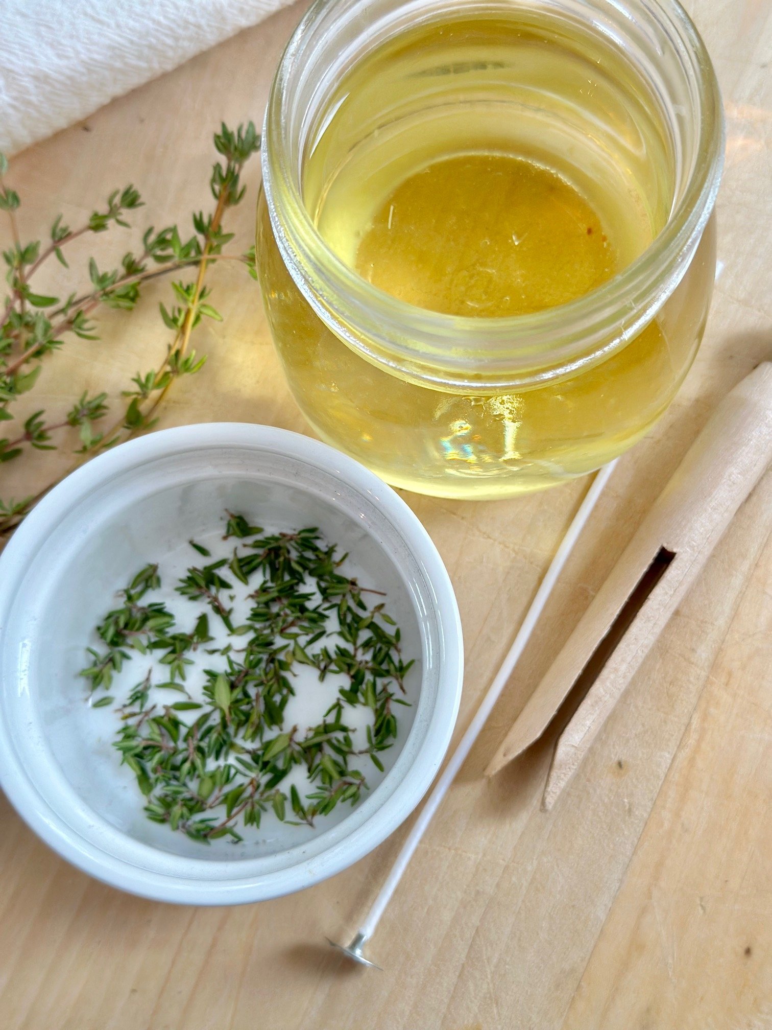 Wax in jar, thyme in a white bowl. 