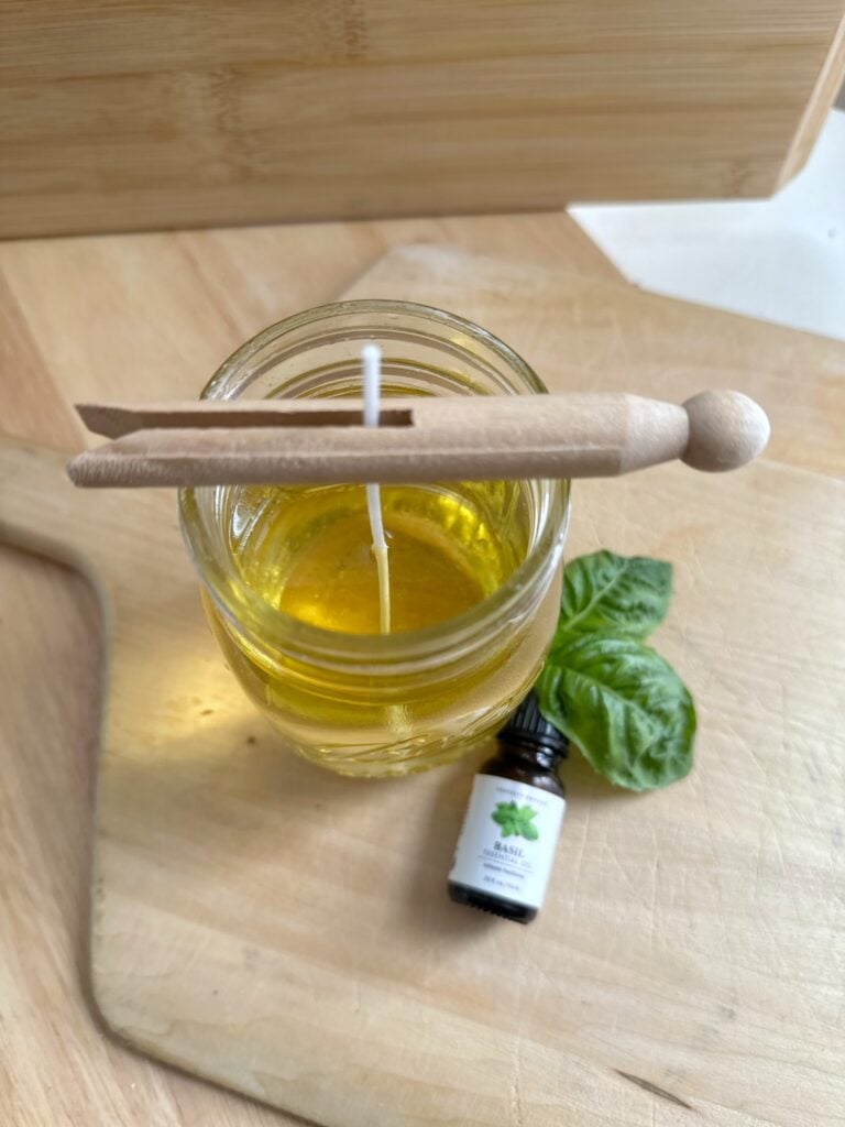 A clothes pin placed across the top of the jar to hold the wick in the center of the candle. 