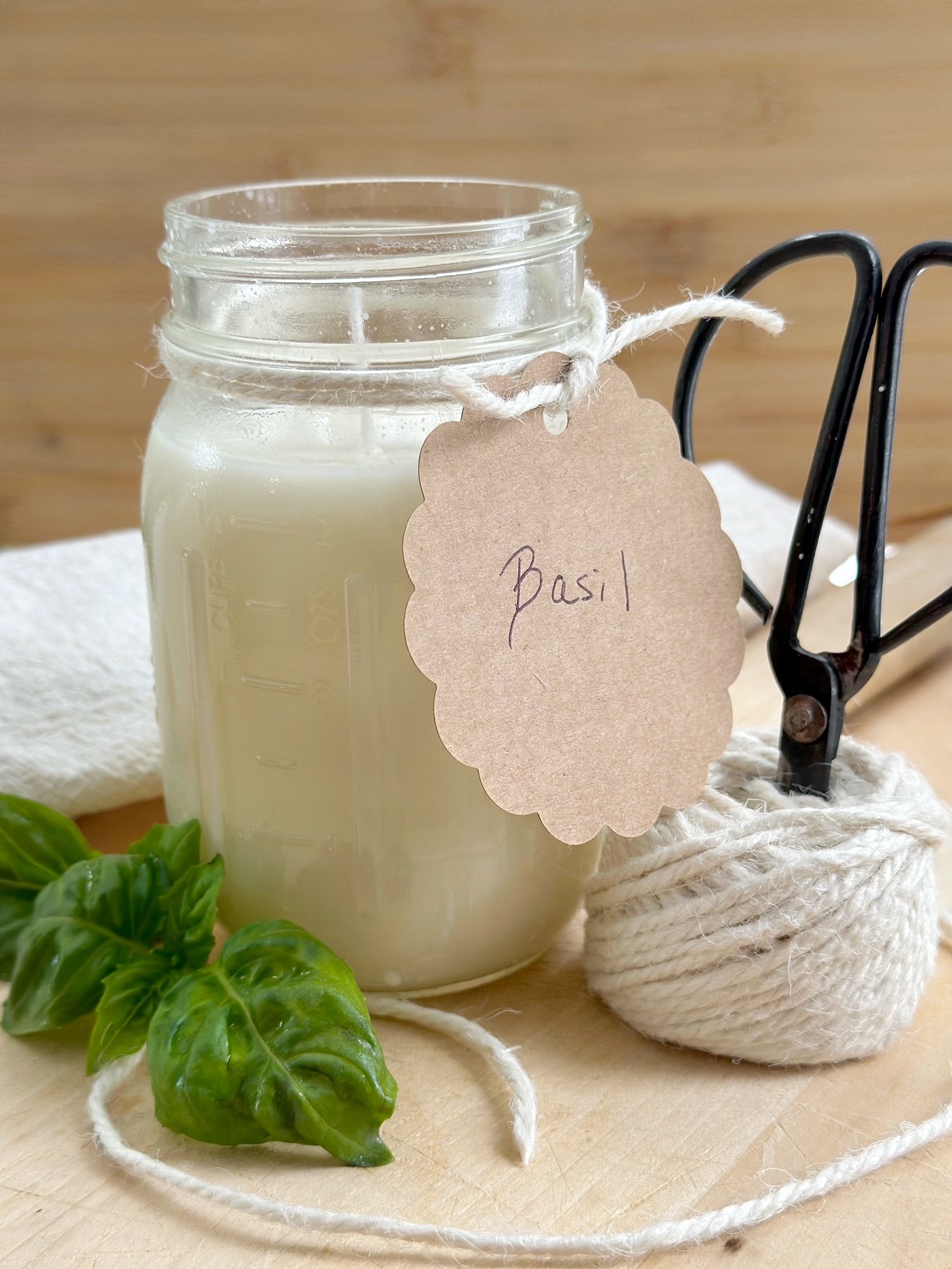 The basil scented candle with a basil tag on it with twine.