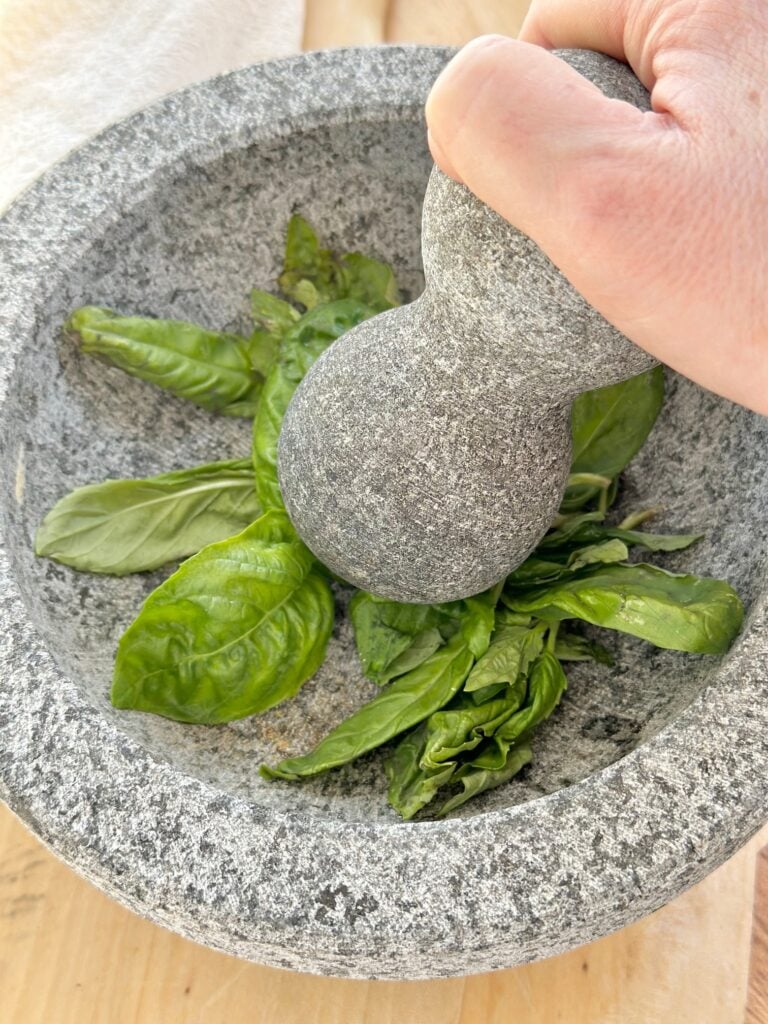 Mortar and pestle with basil leaves. 