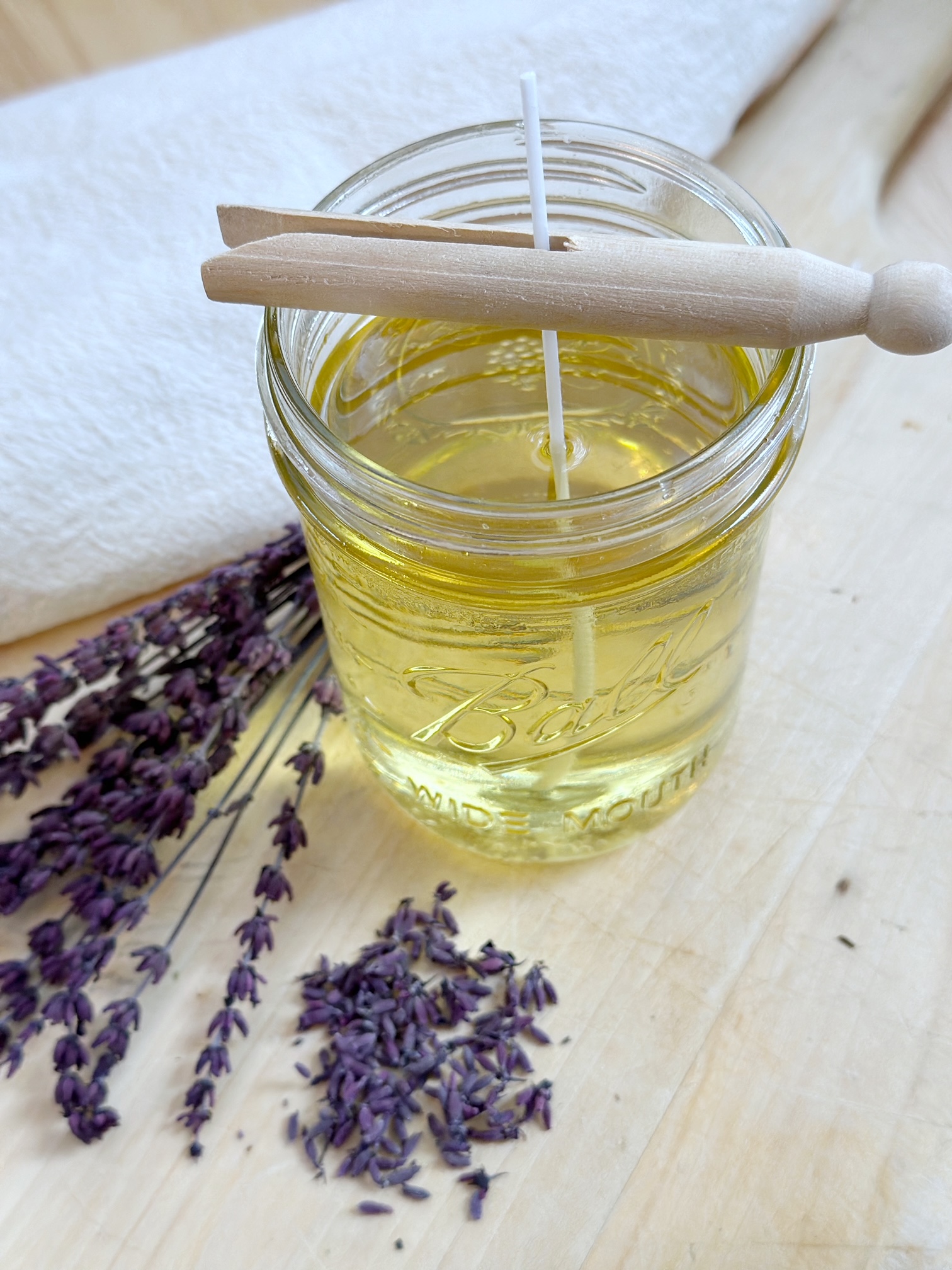 Jar of melted wax with a clothes pin holding the wick in the center. 