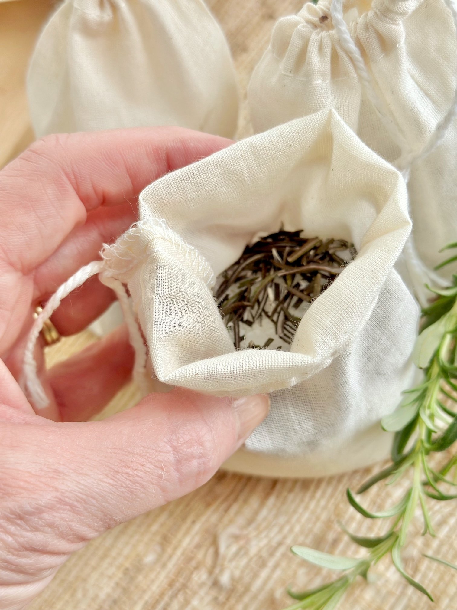 Me holding an open sachet with dried rosemary. 