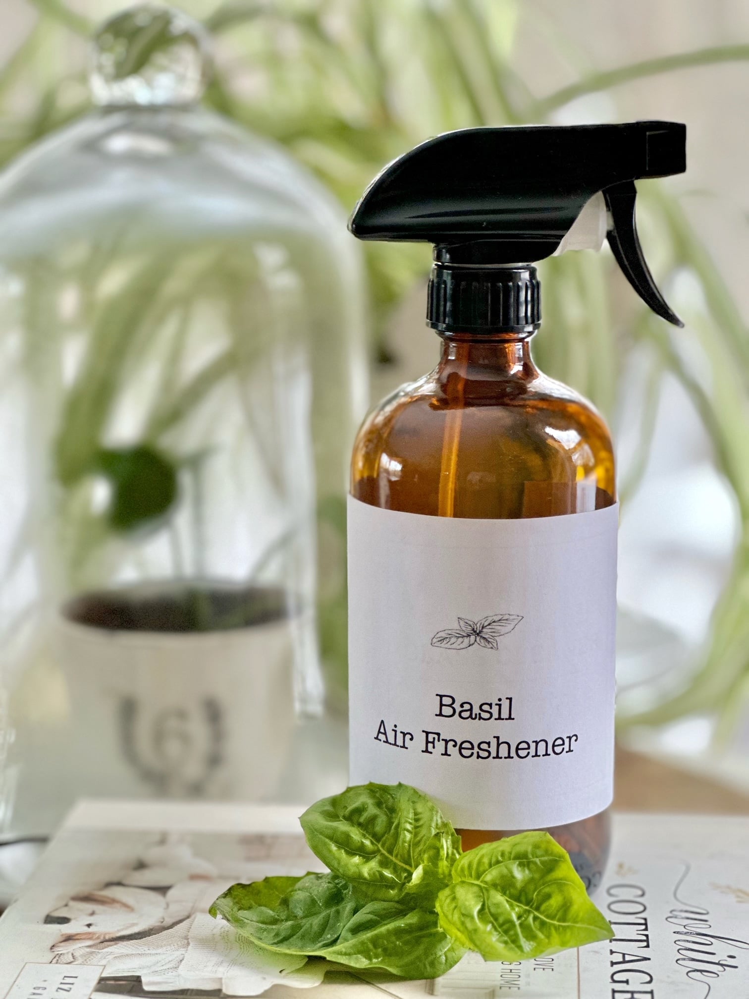 Air freshener in a spray bottle with a sprig of basil next to it. 