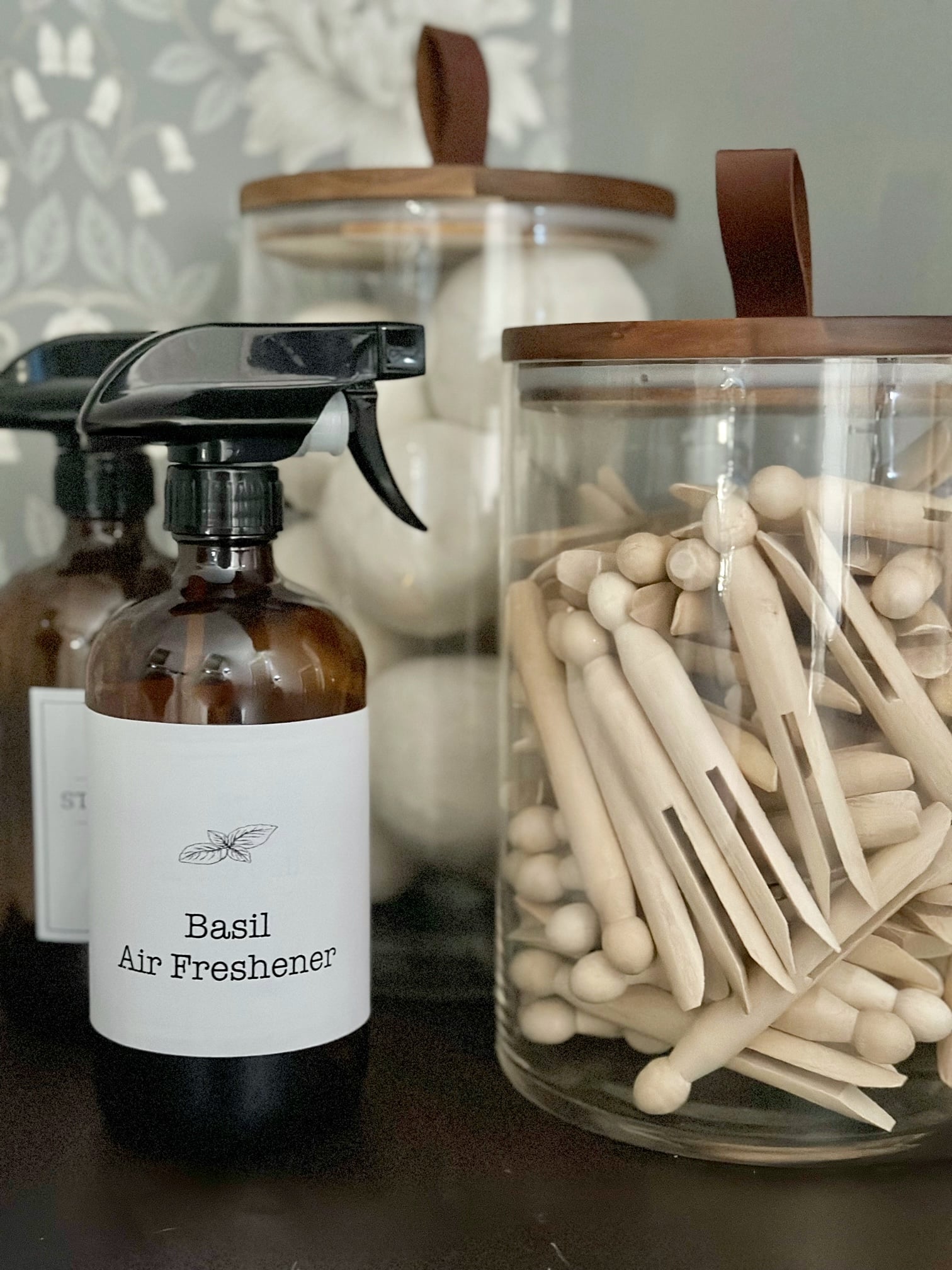 Basil Air freshener in laundry room with canisters of clothes pins and dryer balls. 