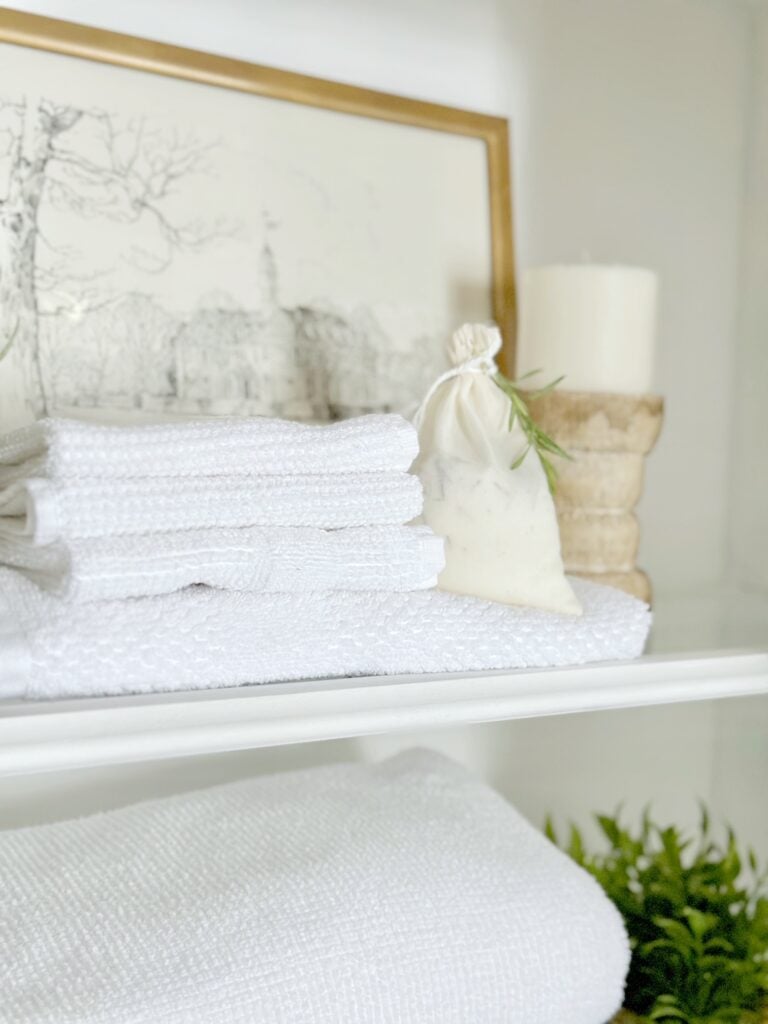 An herb sachet sitting on towels in a linen cabinet. 