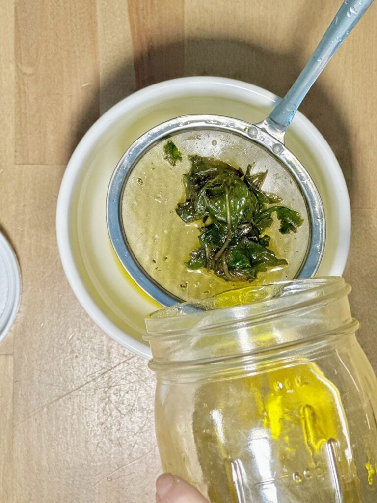 Straining the basil from the oil to separate. 