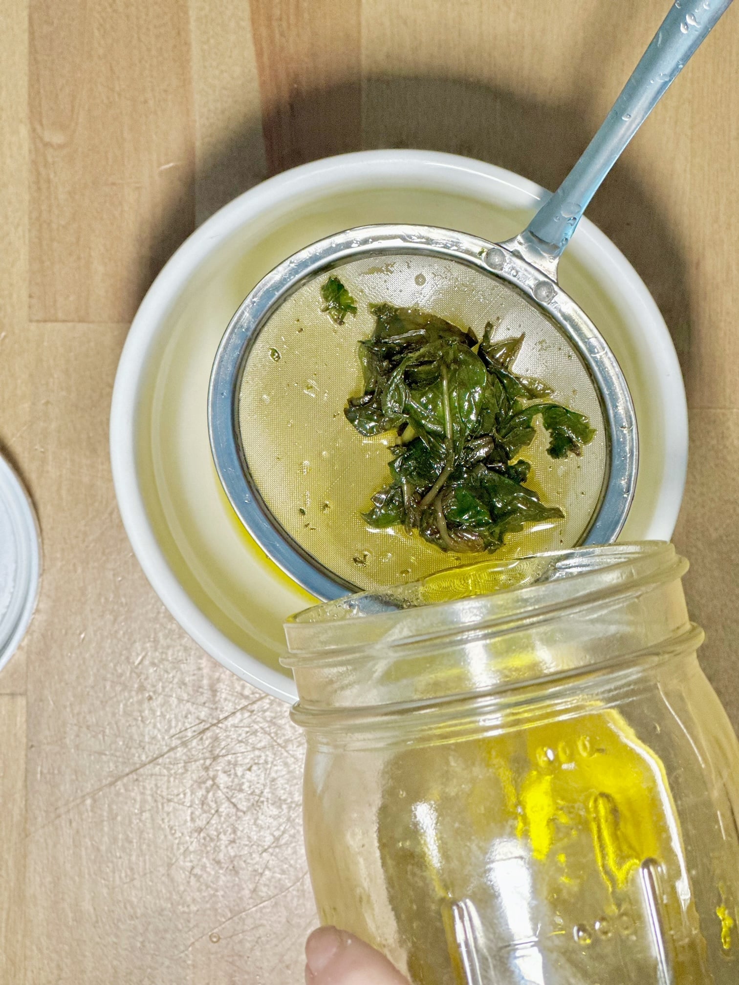 pouring basil through a strainer.
