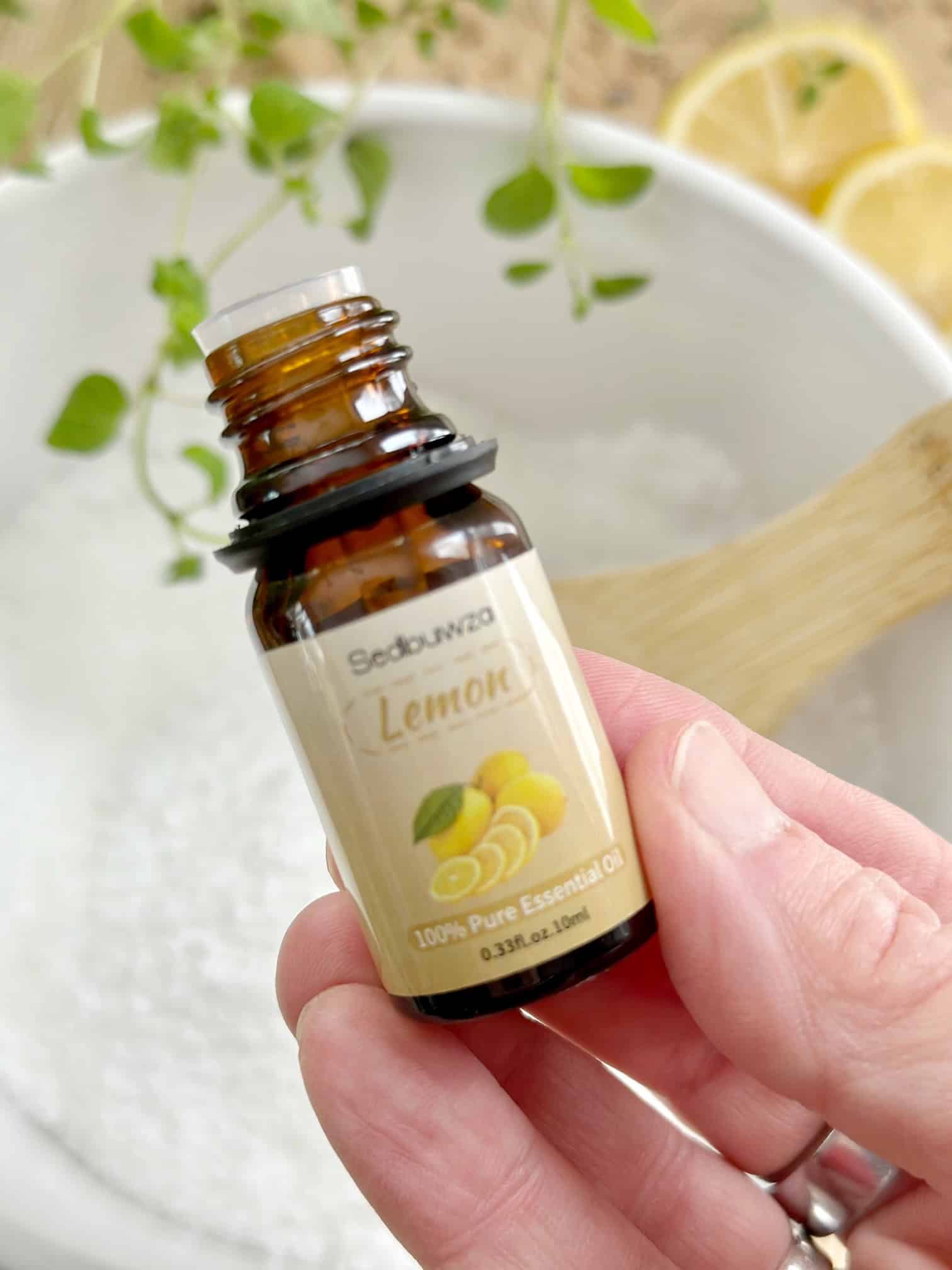 Holding a bottle of lemon essential oil.