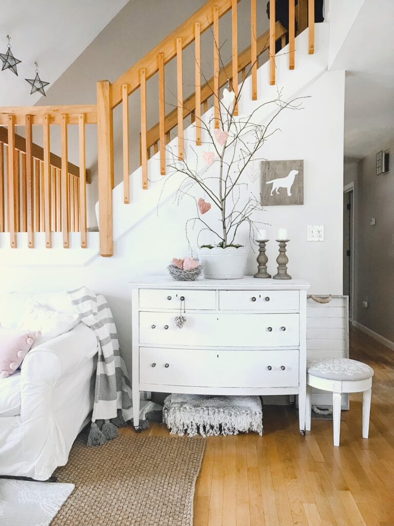 Our cozy living room with a large white pot with foraged branches and hanging yarn hearts to create a Valentine's Day Tree. 