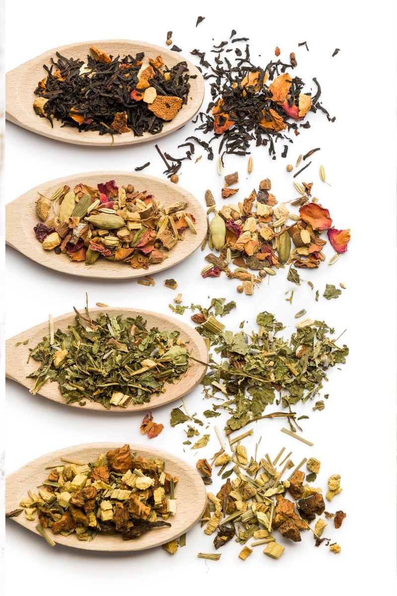 Fresh herbs for tea on wooden spoons.