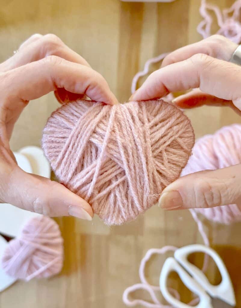 Yarn wrapped heart in hands. 