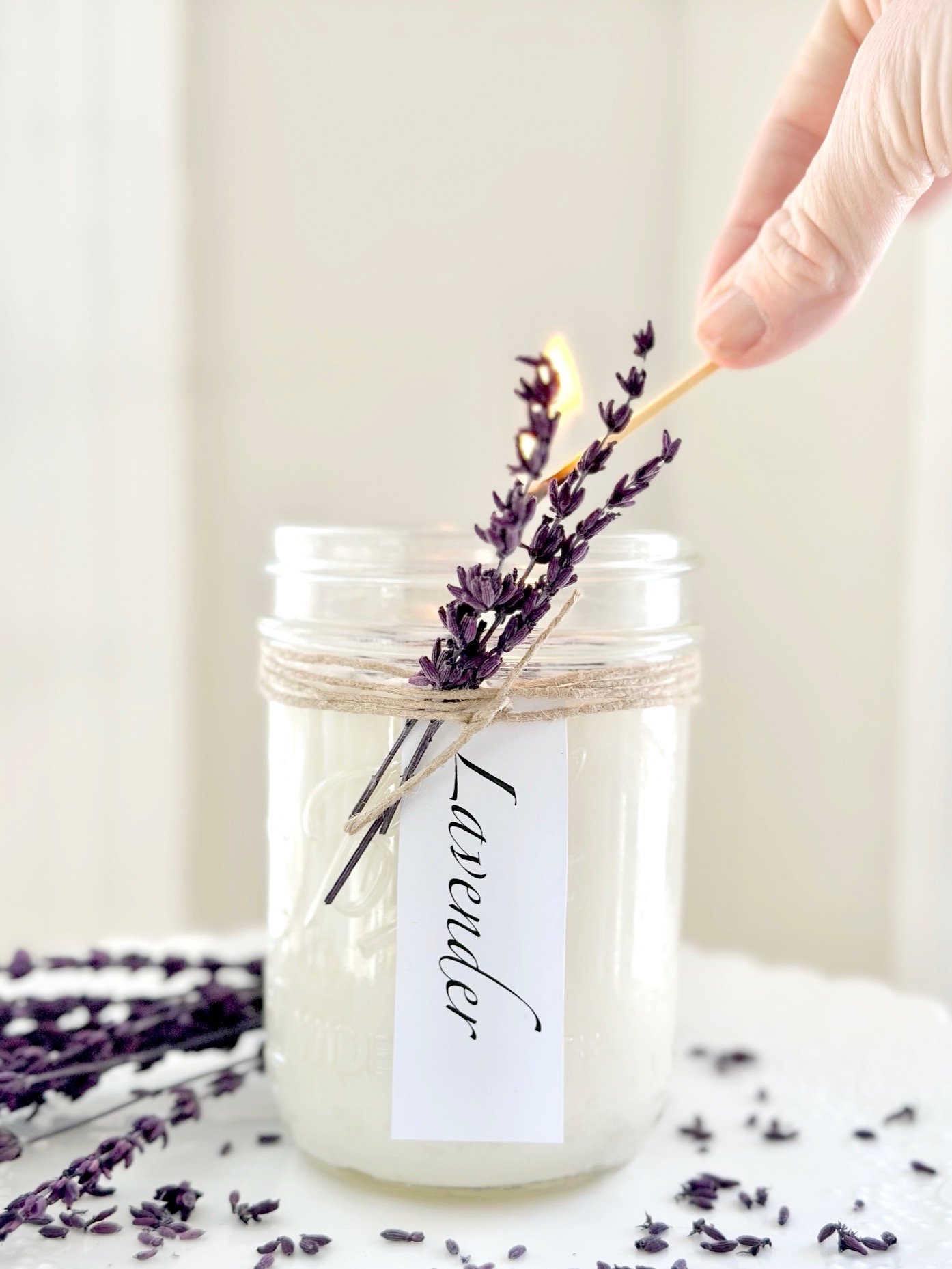 A candle in a jar with lavender tied with twine.