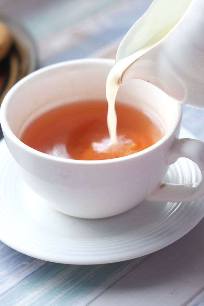 Pouring milk into a cup of hot tea. 